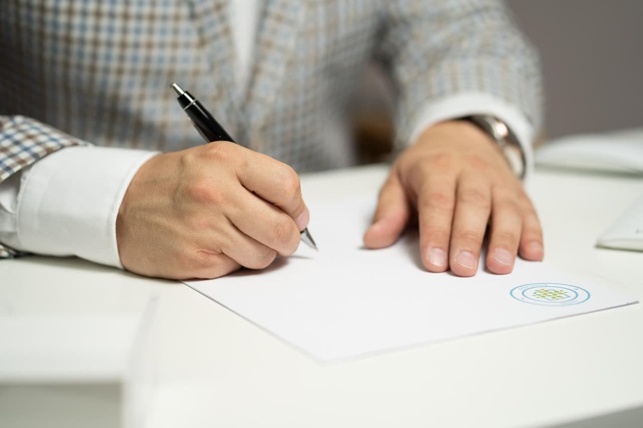 Person signing a document at a desk
