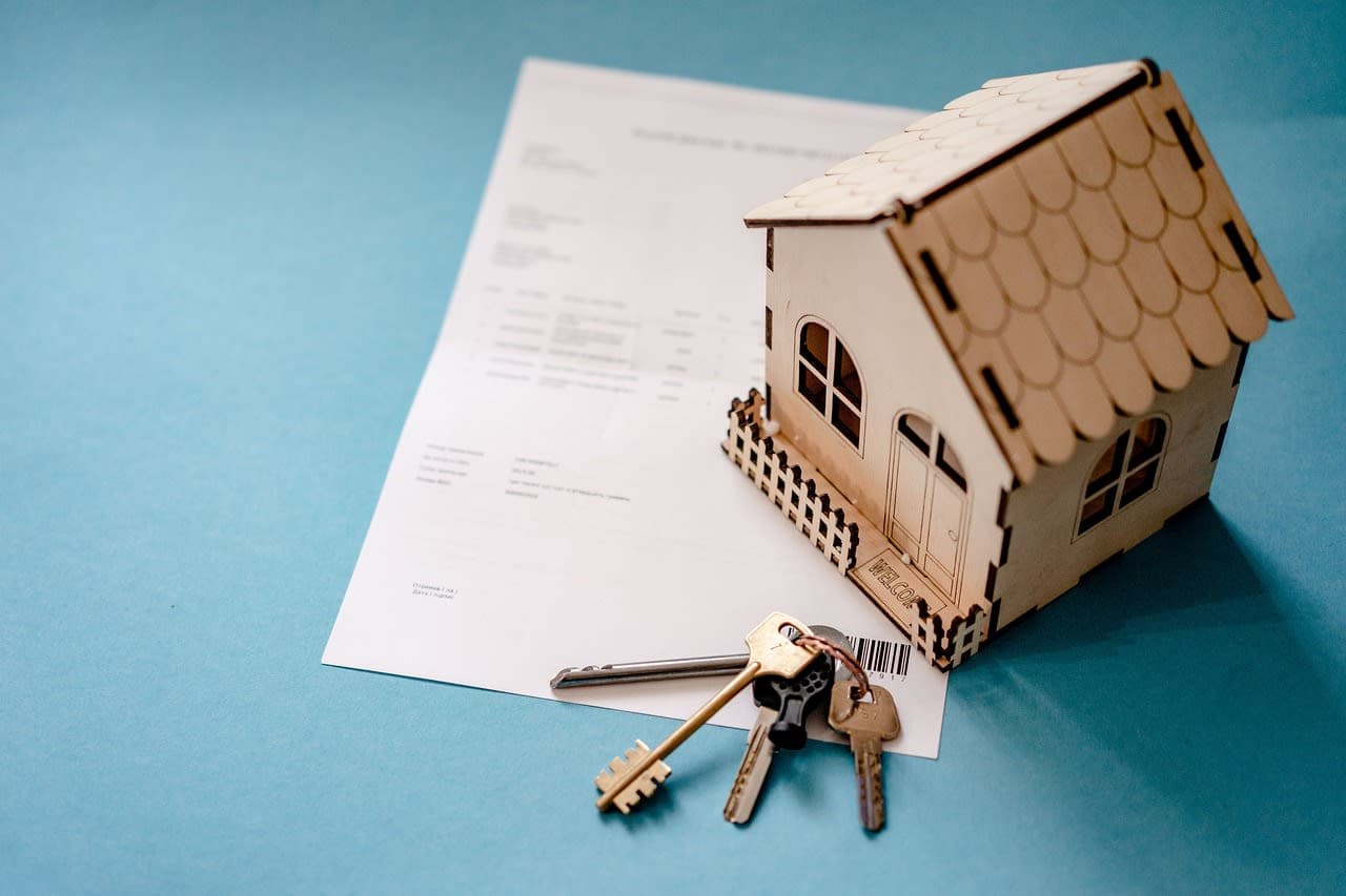 Keys and a contract beside a small model house